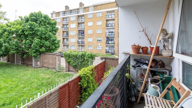 Ein Balkon mit Blumentöpfen, einer Statue und verschiedenen Gartengeräten.