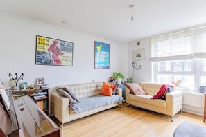A living room with two sofas, a bookshelf, a lamp, and posters on the wall.