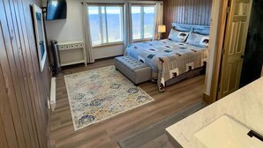 A bedroom with a bed, a TV, a window, and a bathroom with a sink. - Land's End 3 - The Yeti's Den - Snowshoe, Sunset Views! (Snowshoe)