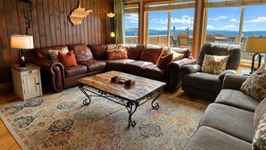 A cozy living room with a brown leather sofa, a gray armchair, and a wooden coffee table. - Land's End 3 - The Yeti's Den - Snowshoe, Sunset Views! (Snowshoe)