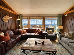 A cozy living room with a sectional sofa, a wooden coffee table, and a view of the mountains through large windows.