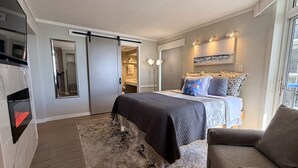 A modern hotel room with a bed, a sofa, a flat-screen TV, and a sliding door leading to a bathroom. - SIPPING ON SUNSHINE/OCEANFRONT/PRIME LOCATION (Myrtle Beach)