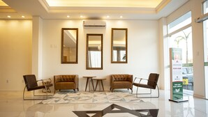 A spacious lobby with a polished floor, three sofas, a small table, and three wall-mounted mirrors.