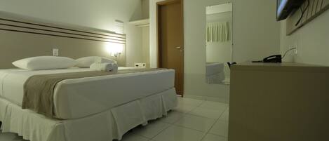 A hotel room with a bed, bedside table, and a flat-screen TV mounted on the wall.