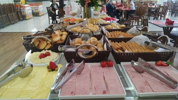 A buffet with various food items including pastries, bread, and deli slices.