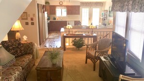 A living room with a sofa, a coffee table, a television, and a dining area with a table and chairs.