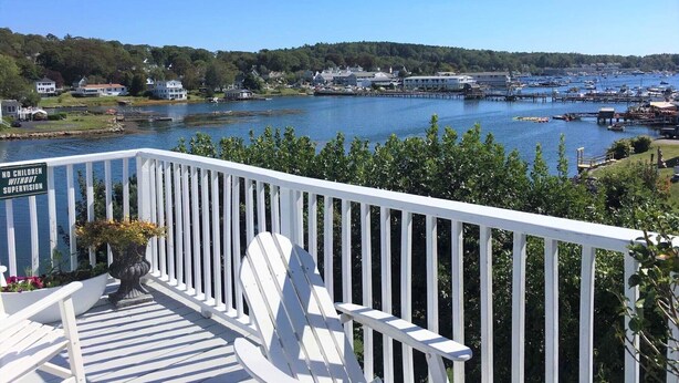 A deck with a view of a harbor, a sign prohibiting children without supervision, and a chair.