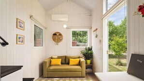 A cozy room with a sofa, a potted plant, and a view of the outdoors.