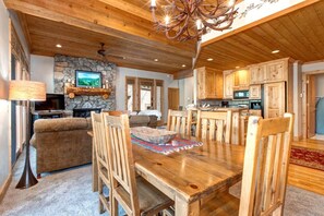 A spacious living room with a fireplace, a dining area with wooden furniture, and a kitchen with wooden cabinets.