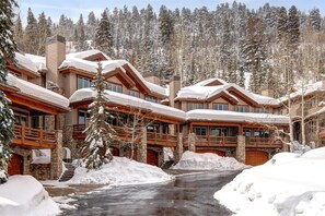 Eine Lodge mit mehreren Holzhütten, Steinmauern und einer verschneiten Landschaft.