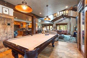 Ein geräumiges Zimmer mit Poolbillard, Holzmöbeln und einer Treppe zu einer oberen Ebene.