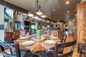 A spacious dining area with a round table set for six, surrounded by wooden chairs.