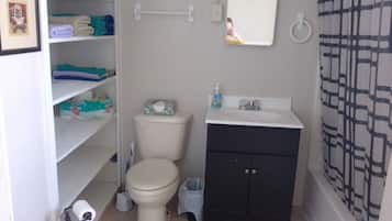 Een bad/douchecombinatie, een haardroger, handdoeken, toiletpapier