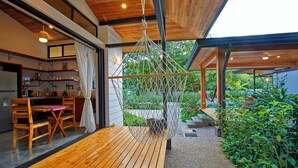 Una cucina moderna con mobili in legno, un'area pranzo con tavolo e sedie, e una poltrona sospesa in giardino.