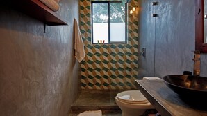 Un bagno con parete a motivo geometrico, un'ampia finestra, un water e un lavabo a incasso.