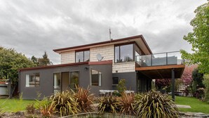 A modern two-story house with a balcony, large windows, and a well-maintained garden. - Pip's Lakeview Retreat (Wanaka)