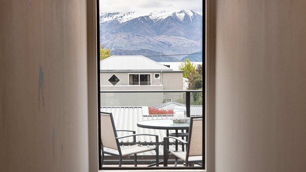 A balcony with a table and chairs, overlooking a mountain range. - Pip's Lakeview Retreat (Wanaka)