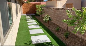 Stroll through the beautifully maintained garden, featuring a lush lawn and stepping stones leading to the building.