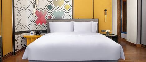 Una habitación de hotel con una cama grande, una mesita de noche con lámpara y un papel tapiz estampado.