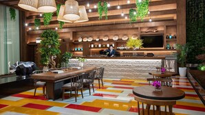 A modern bar area with wooden accents, hanging plants, and a colorful floor pattern.