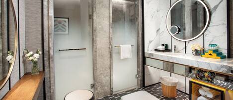 Une salle de bain moderne avec une douche à parois de verre, un meuble-lavabo en marbre et un miroir rond.