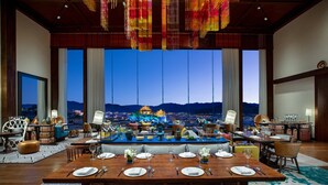 A dining area with a large table set for six, a bar area, and a view of a cityscape at dusk.