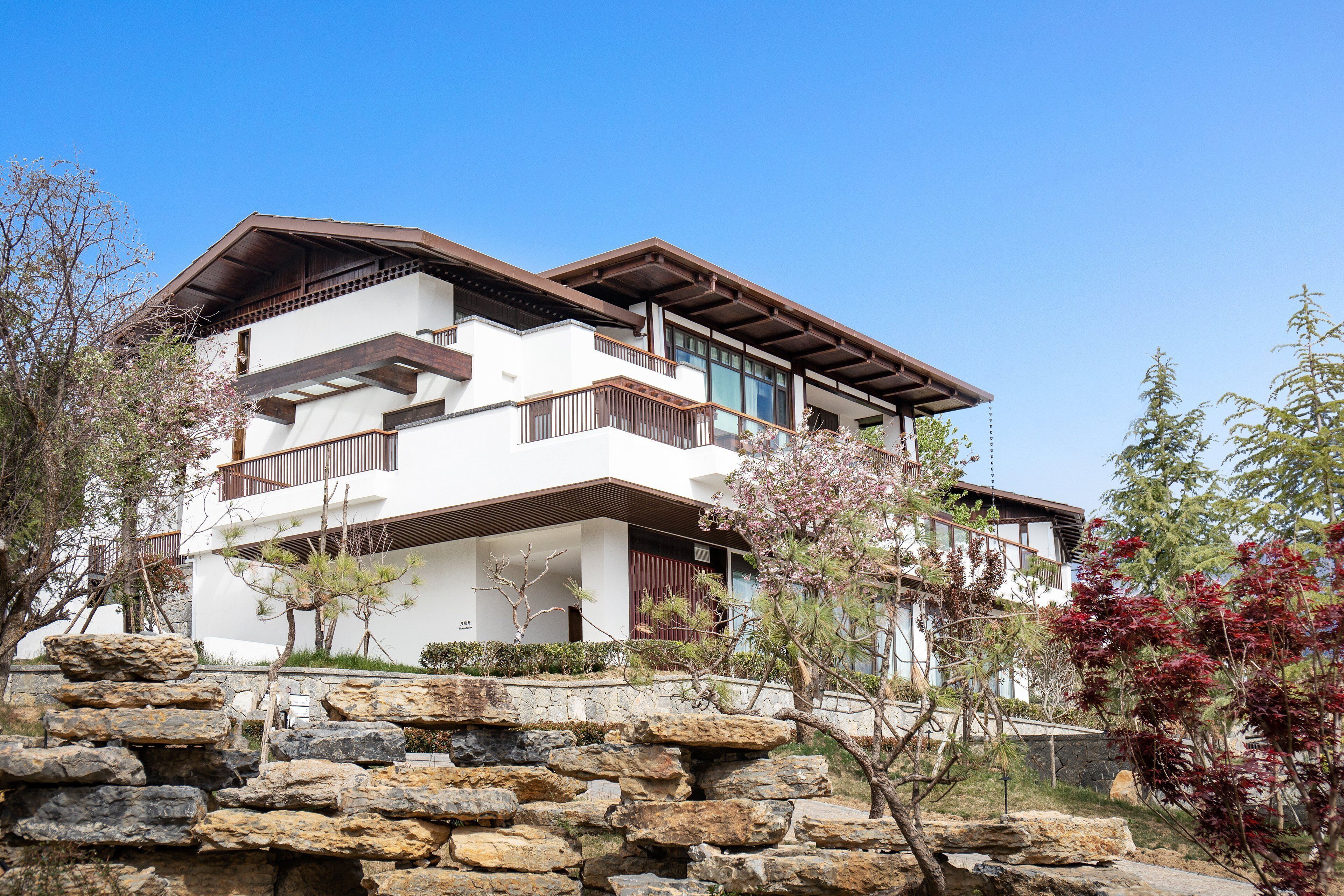 A multi-story building with a modern architectural design, featuring balconies and a stone facade.