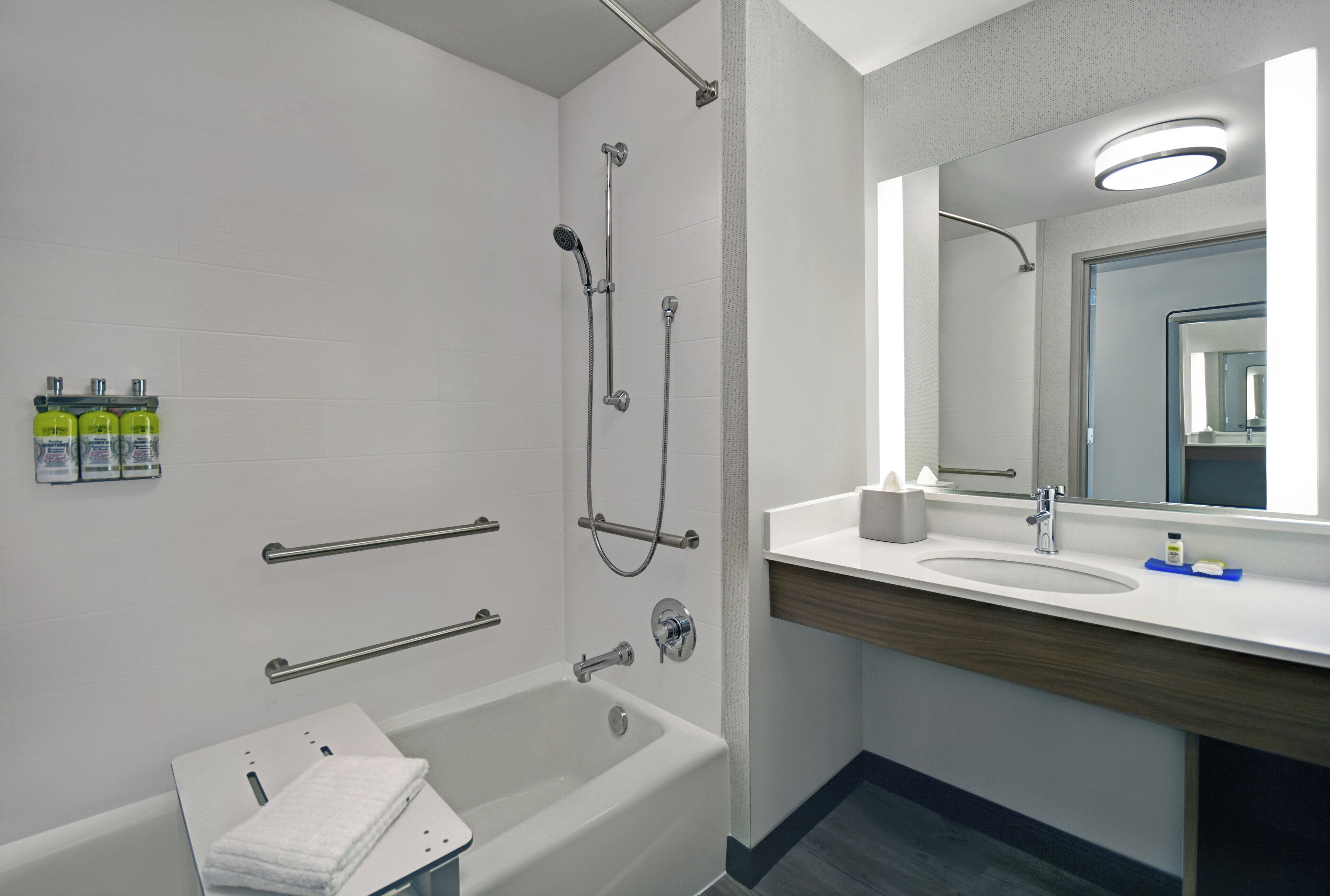 A modern bathroom with a bathtub, shower, and vanity with a mirror.