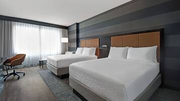A hotel room with two beds, a desk, and a chair.