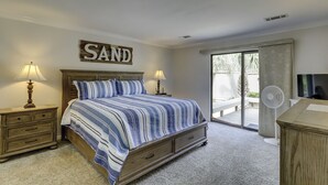 Une chambre à coucher comprenant un lit, deux tables de chevet, une commode, une grande fenêtre et une porte-fenêtre coulissante donnant sur un espace extérieur.