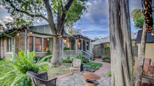 A patio area with stone flooring, a wicker chair, and a decorative lantern. - New Braunfels Bungalow~Near Downtown (New Braunfels)
