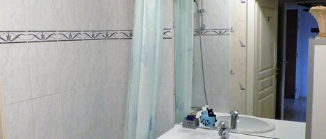A bathroom with a white sink, a mirror, and a shower.
