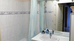 Een bad/douchecombinatie, een haardroger, handdoeken, zeep