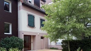 En boligbygning med hovedindgang, indkørsel og en lille have med forskellige planter.