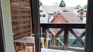 En balkon med gelænder i træ, et bord og stole.