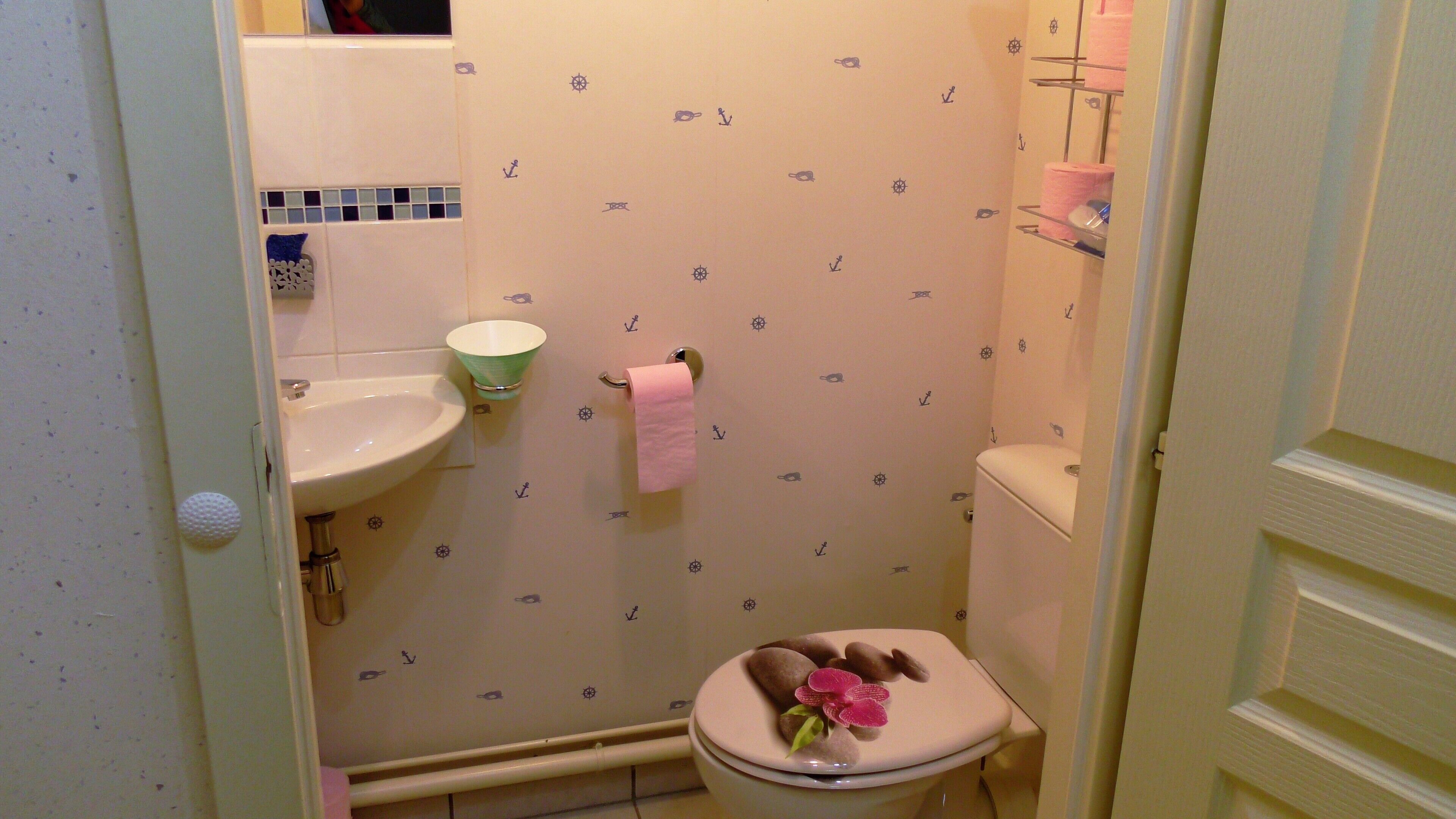 A bathroom with a toilet, sink, and a small shelf with toiletries.