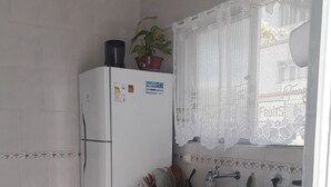 Pieni, käytännöllinen keittiö, jossa on jääkaappi, pesuallas ja liesi.