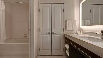 A bathroom with a walk-in shower, a double door vanity with a mirror, and a sink.