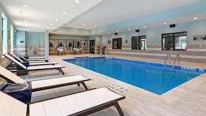 Una piscina con sillas de descanso, vestuarios y equipo de ejercicio.