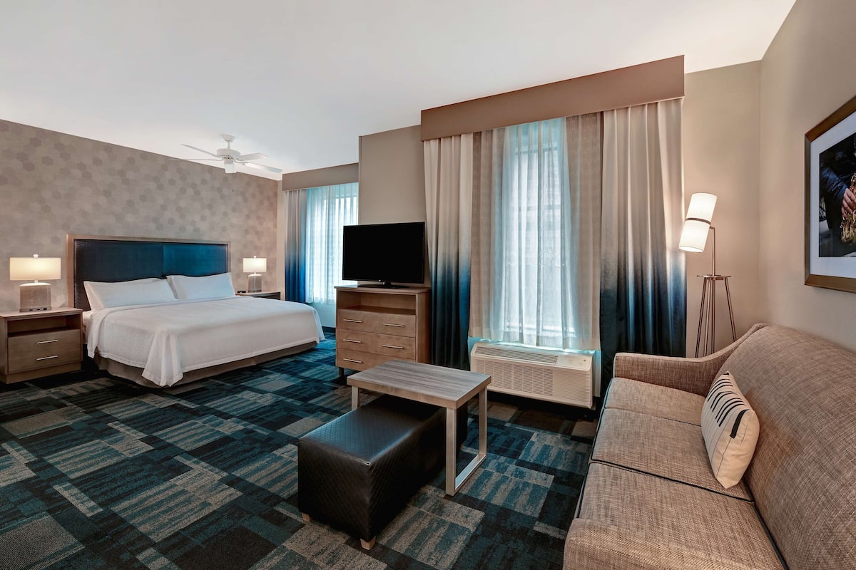 Habitación de hotel con cama, televisión, sofá, mesa de centro y escritorio.