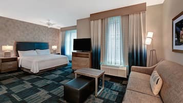 A hotel room with a bed, a TV, a sofa, a coffee table, and a desk.
