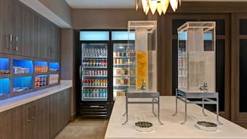 A modern kitchen with a central island, built-in cabinets, and a refrigerator stocked with beverages and snacks.