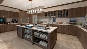 Una cocina moderna con armarios de madera, una isla central con cubierta de vidrio y una estación de café integrada.