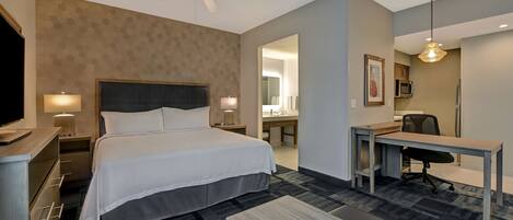 A hotel room with a bed, desk, chair, and a ceiling fan.