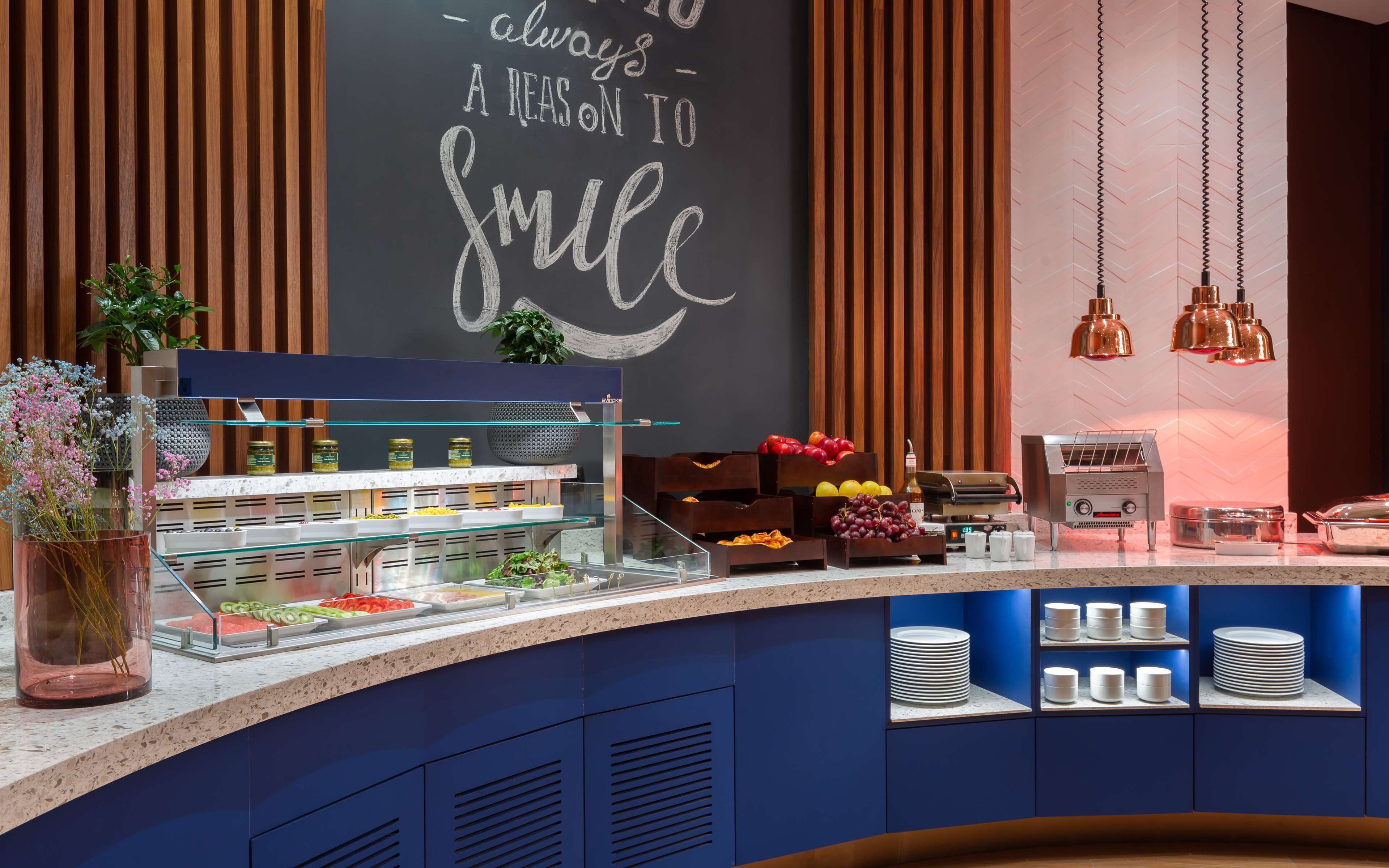 Un comptoir-bar moderne, doté d’un tableau noir, d’une machine à café et de divers produits alimentaires.