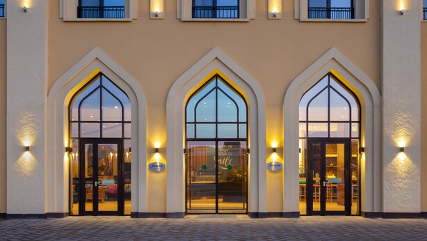 L’entrée d’un hôtel, ornée de trois fenêtres en arc, chacune portant une enseigne indiquant « Hampton ».