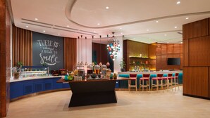 Un espace bar moderne doté d’un îlot central, de tabourets de bar et d’un luminaire décoratif suspendu.