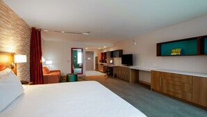 Ein Hotelzimmer mit einem großen Bett, einem Schreibtisch, einem Fernseher und einer Minibar.