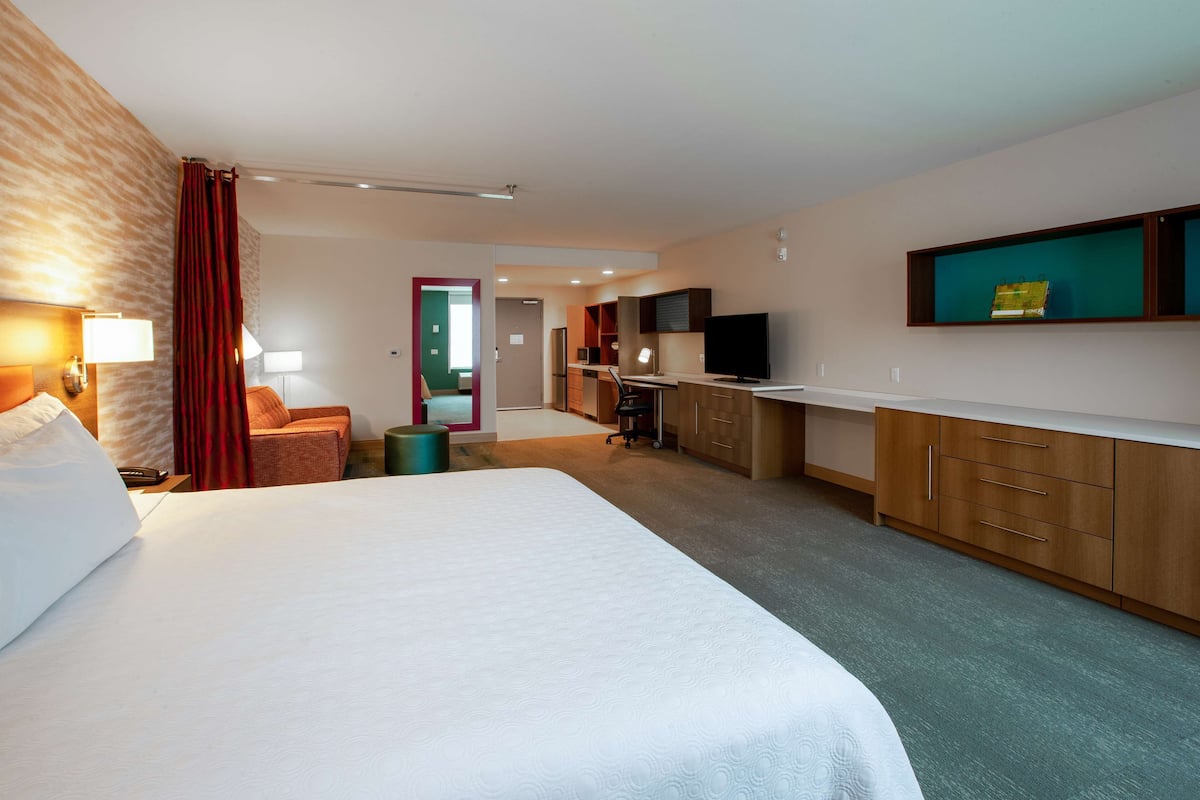 Una habitación de hotel con una cama grande, un escritorio, un televisor y un minibar.