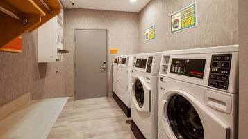 A laundry area with multiple washing machines, a door, and a sign indicating a front desk.